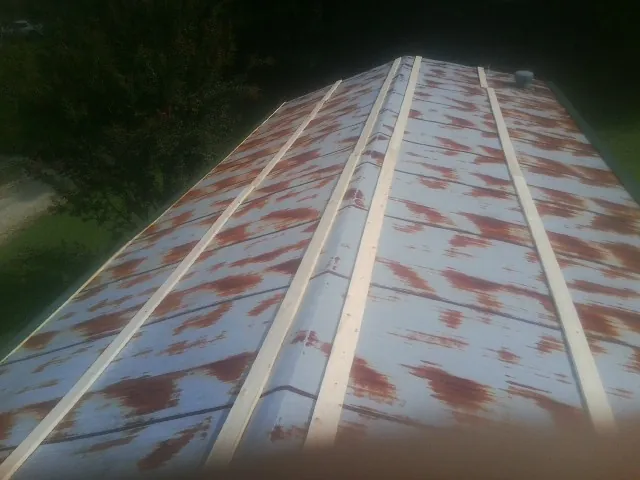 Rusted metal roof panels with new wood purlins before replacement in Highland
